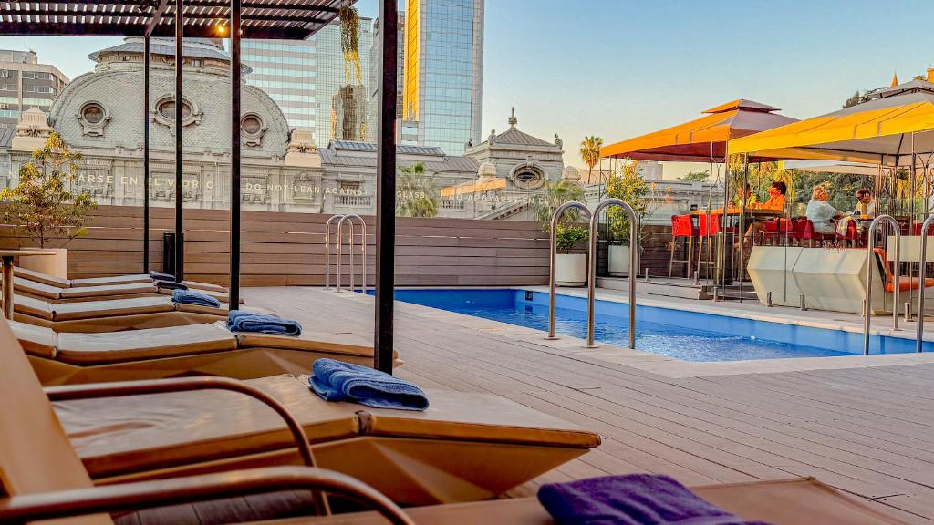 a hotel rooftop with a swimming pool and a building at Mercure Santiago Centro in Santiago