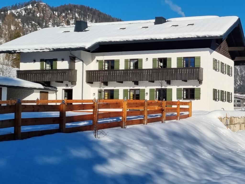 een huis met een hek in de sneeuw bij Zollhaus 65 in Reit im Winkl