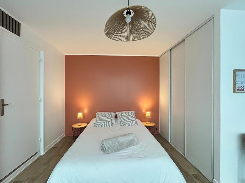 a bedroom with a large white bed with two lamps at Charmant studio avec terrasse in Fécamp