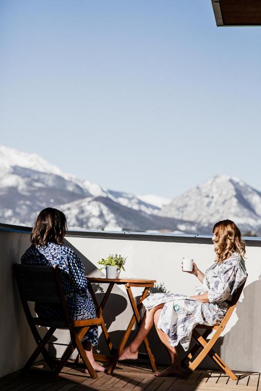 two women sitting at a table on a balcony with snow covered mountains at Shorehouse Hotel in Buena Vista