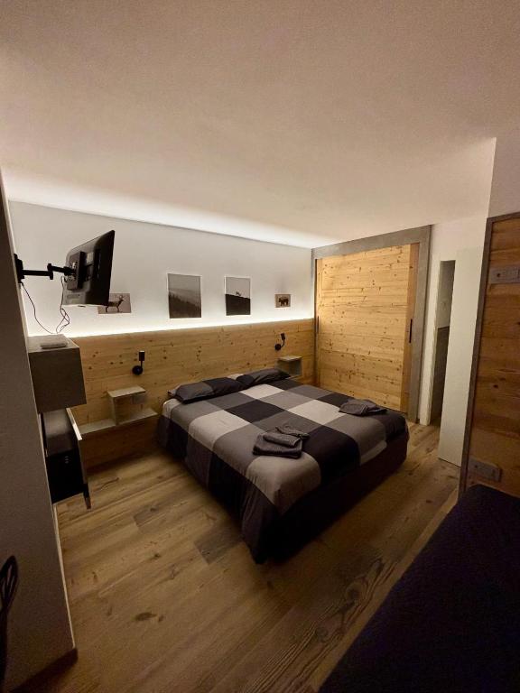 a bedroom with a large bed and a flat screen tv at Fiore delle Alpi in Bellamonte