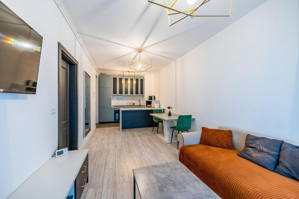 a living room with an orange couch and a kitchen at Apartamente Arad Premium in Arad