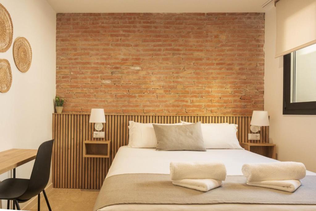 a bedroom with a bed and a brick wall at GuestReady - ARIQUS Apartments in Hospitalet de Llobregat