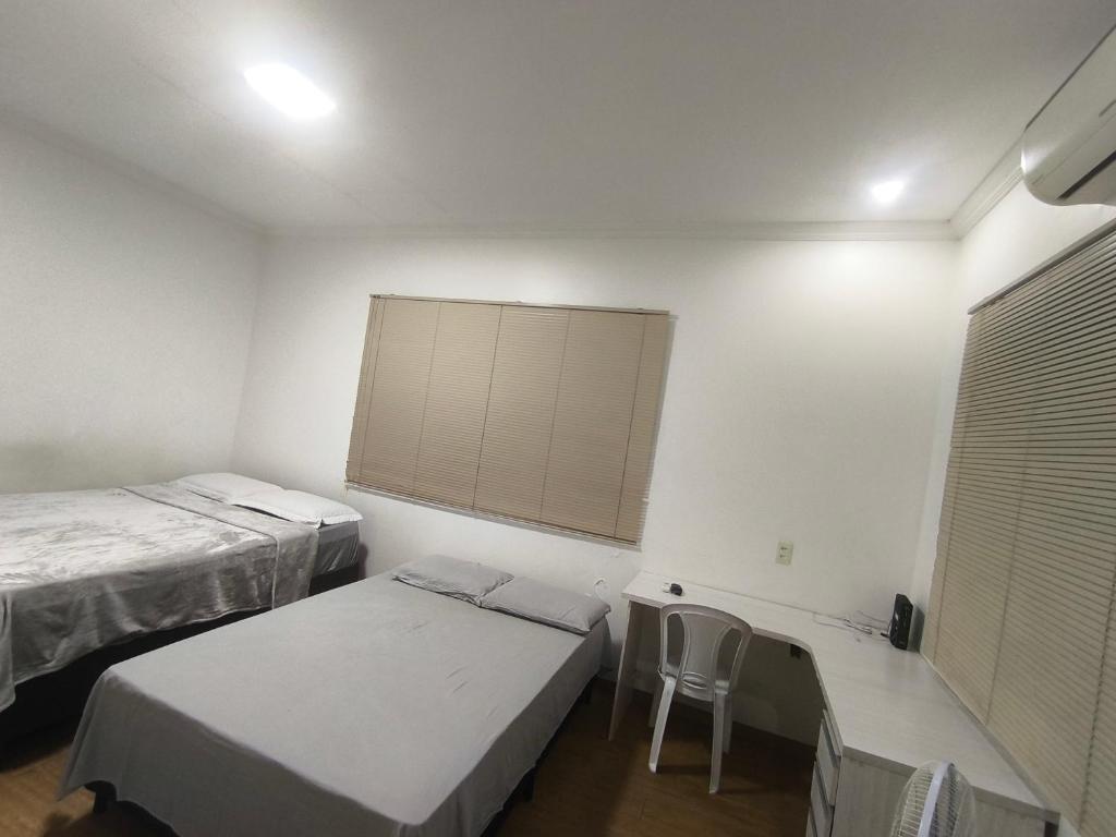 a room with two beds and a table and a window at Varanda das araras in Manaus
