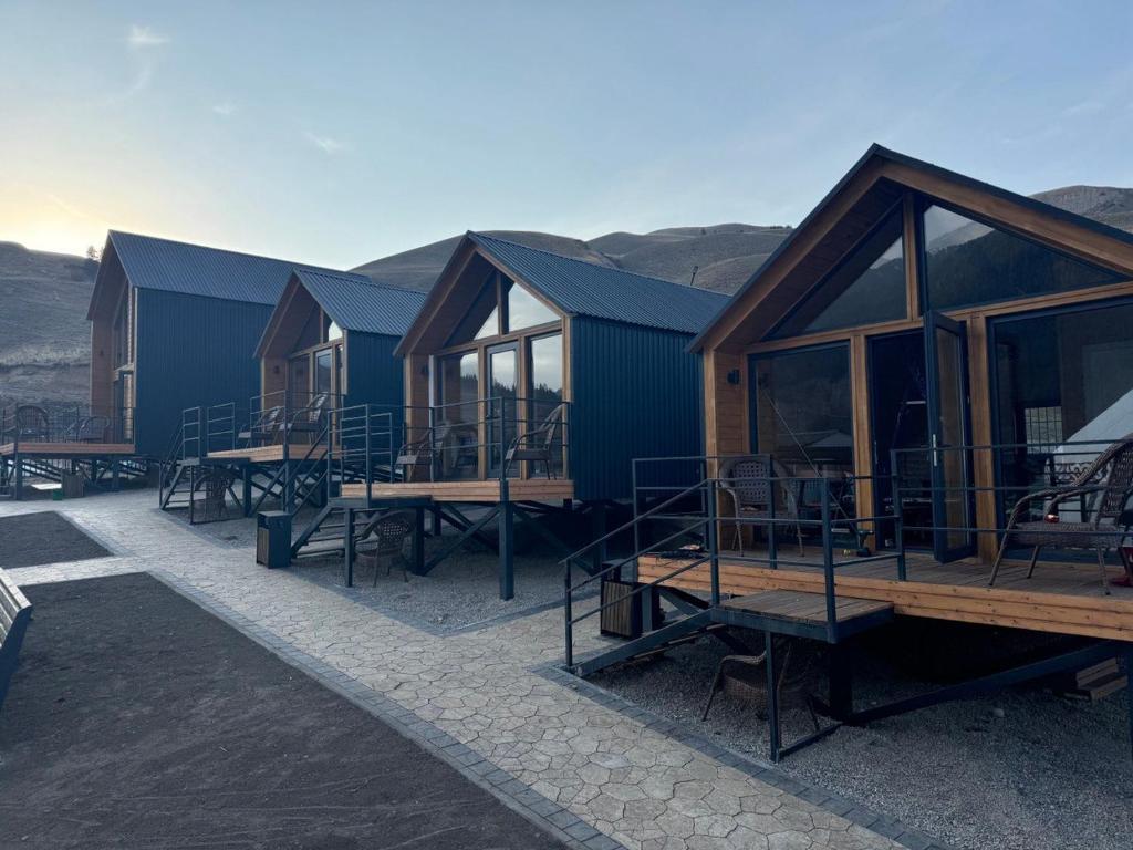 una hilera de cabañas con mesas y ventanas en Mountain View - Kolsay, en Kurmenty