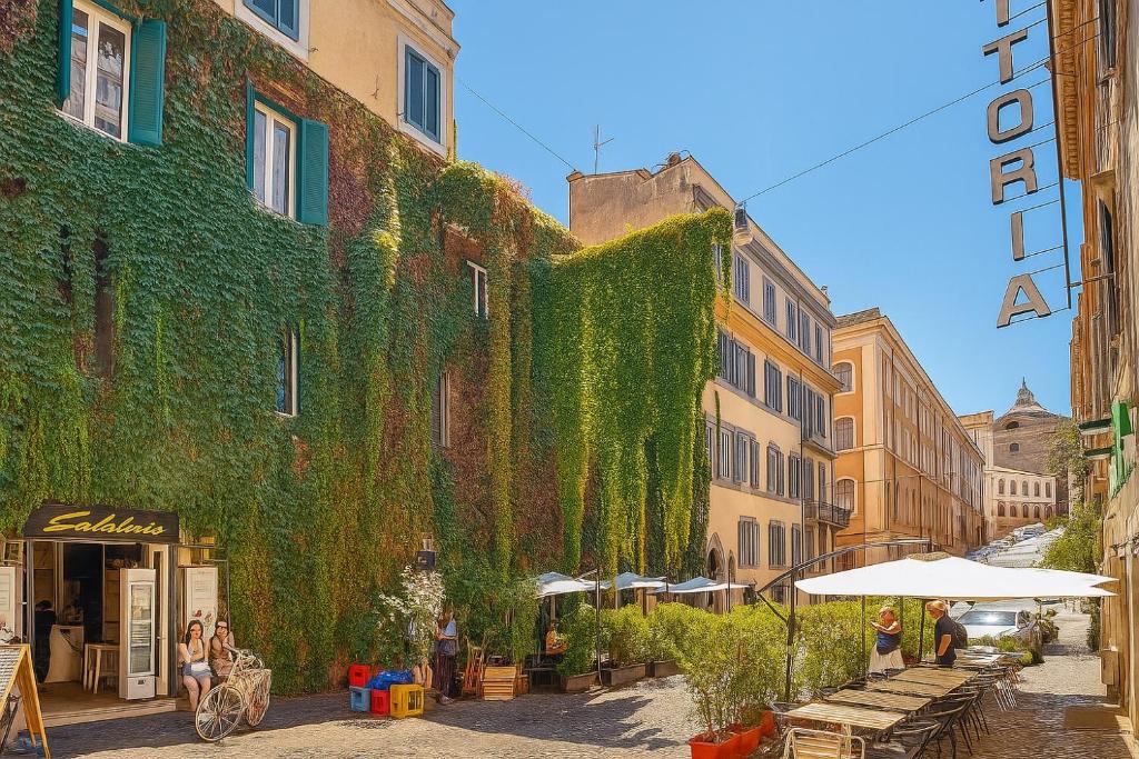 a green ivy covered building with tables and umbrellas on a street at REALE COLOSSEO TREVI HOME - private garden in Rome