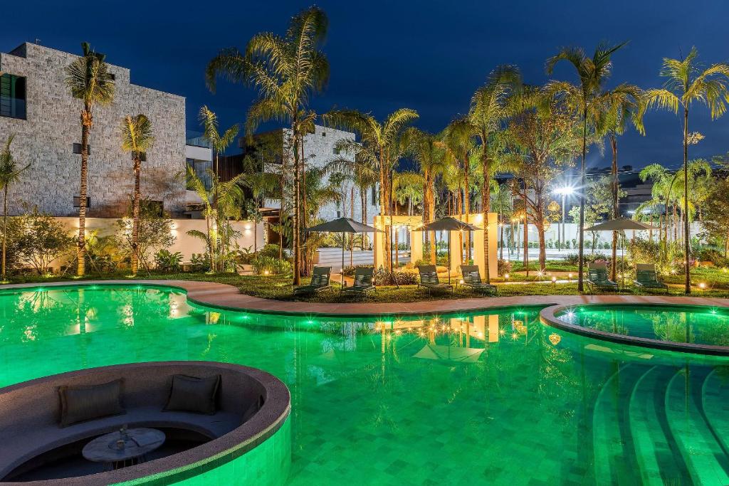ein Swimmingpool mit Palmen vor einem Gebäude in der Unterkunft Riviera | Luxo e Design no Golf – Cond Privativo in Riviera de São Lourenço