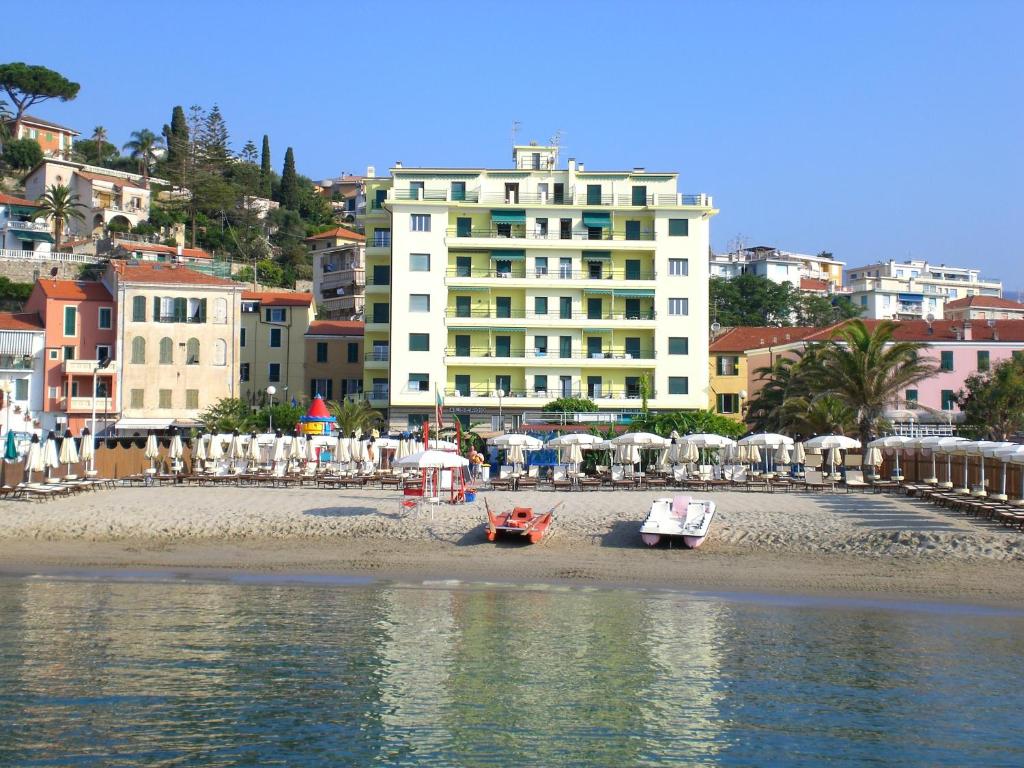 uma praia com barcos na areia e um edifício em Hotel Ideal em Arma di Taggia