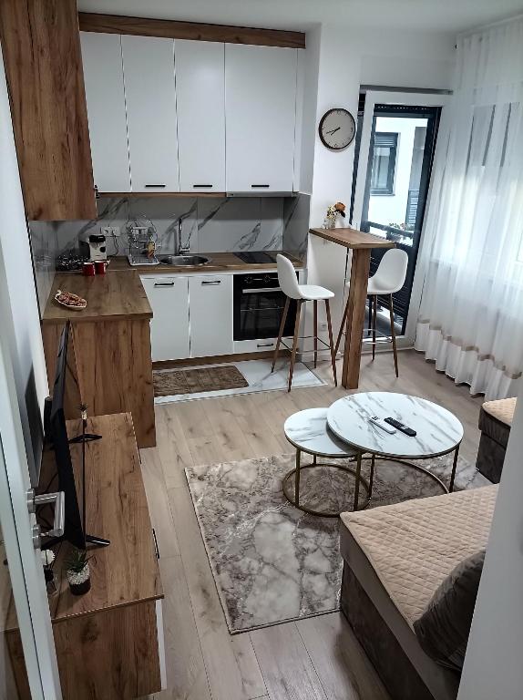 a kitchen and living room with white cabinets and a table at INKOGNITO Centar 39 in Brčko