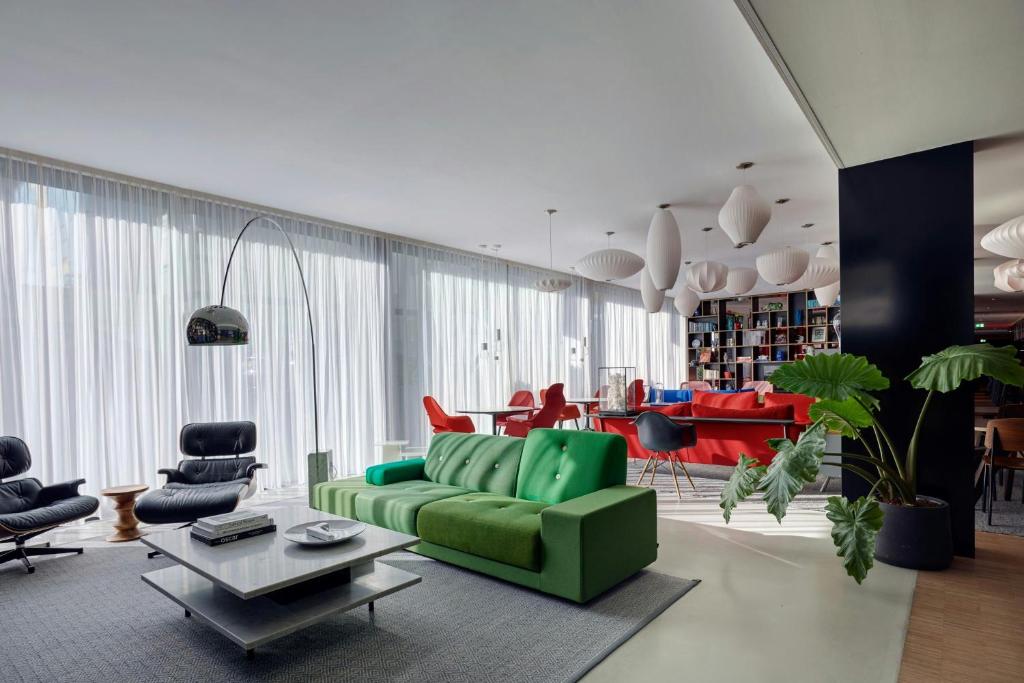 a living room with a green couch and chairs at citizenM Amsterdam South in Amsterdam