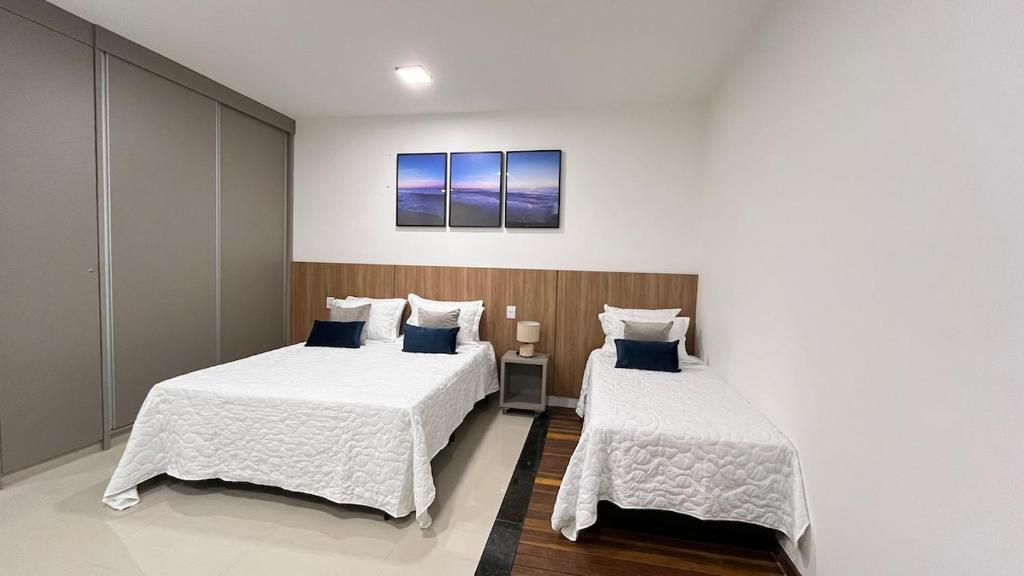 a bedroom with two beds with white sheets and blue pillows at 407-3 · Duplex Sossego in Anápolis