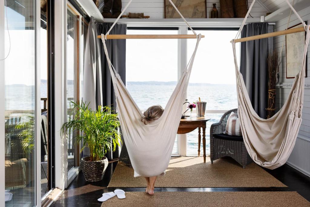 a woman in a hammock in a room with the ocean at Strandflickornas Husen invid Havet in Lysekil