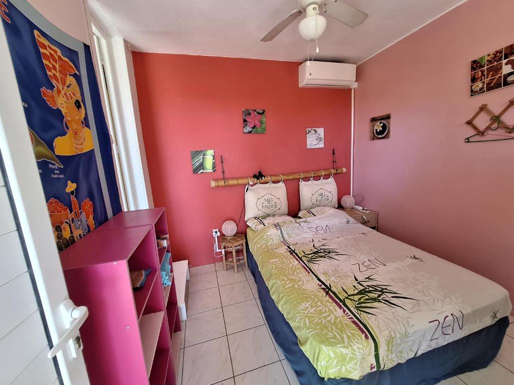 a bedroom with a bed and a pink wall at Gite DANGIEN in Vieux-Habitants