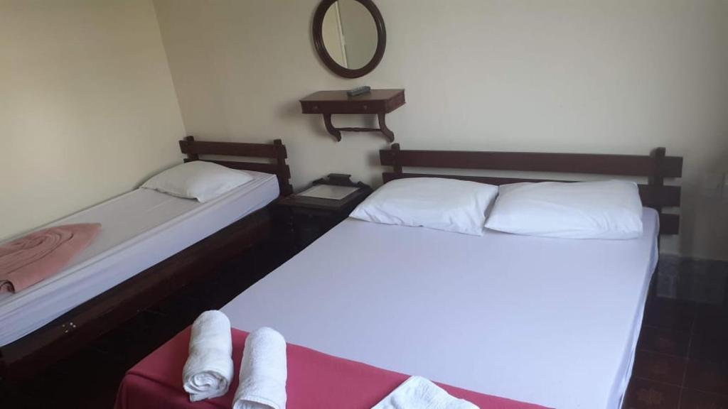two beds in a small room with a mirror at Nova Pousada do Canal in Cabo Frio