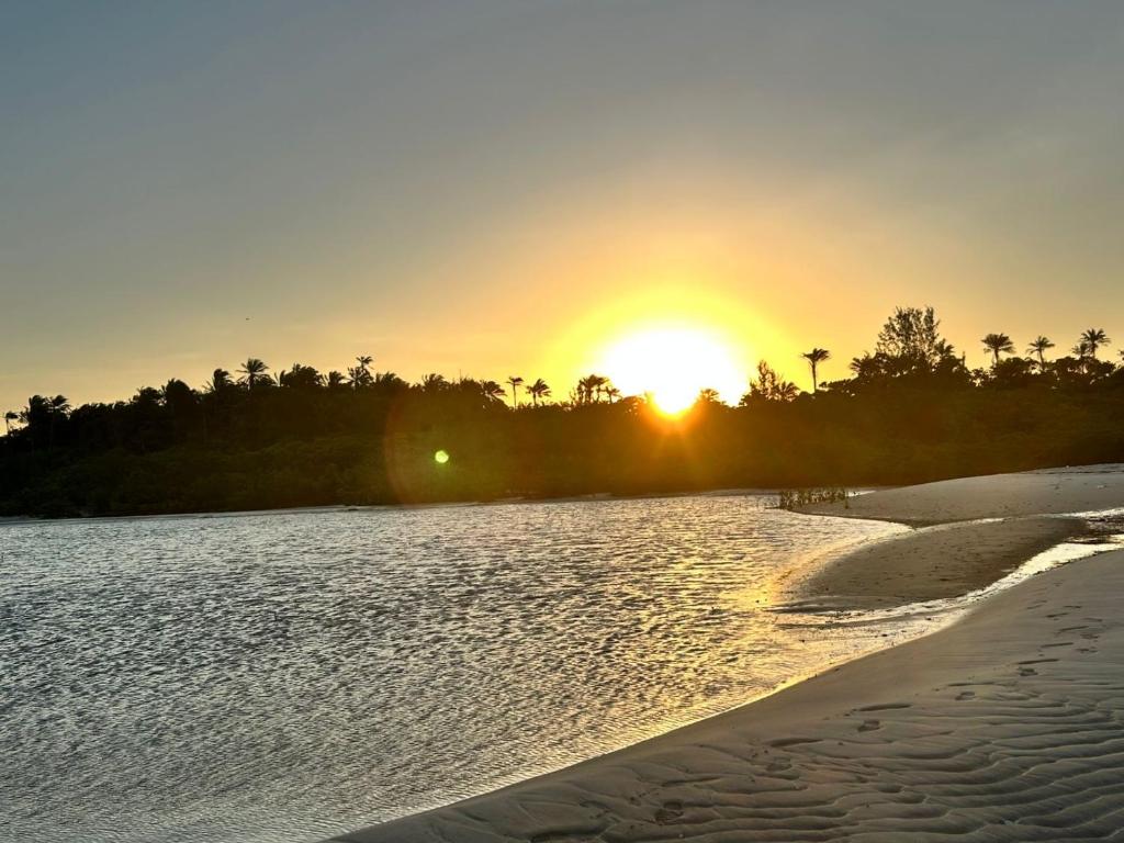 een zonsondergang op een strand met zonsondergang bij Villa Tropicana in Saubara