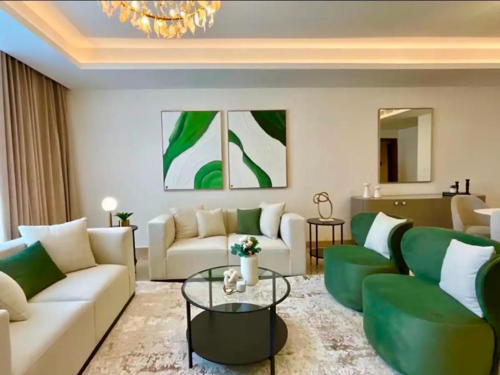 a living room with green furniture and a chandelier at Luxury Apartments in Cairo Festival City in Cairo