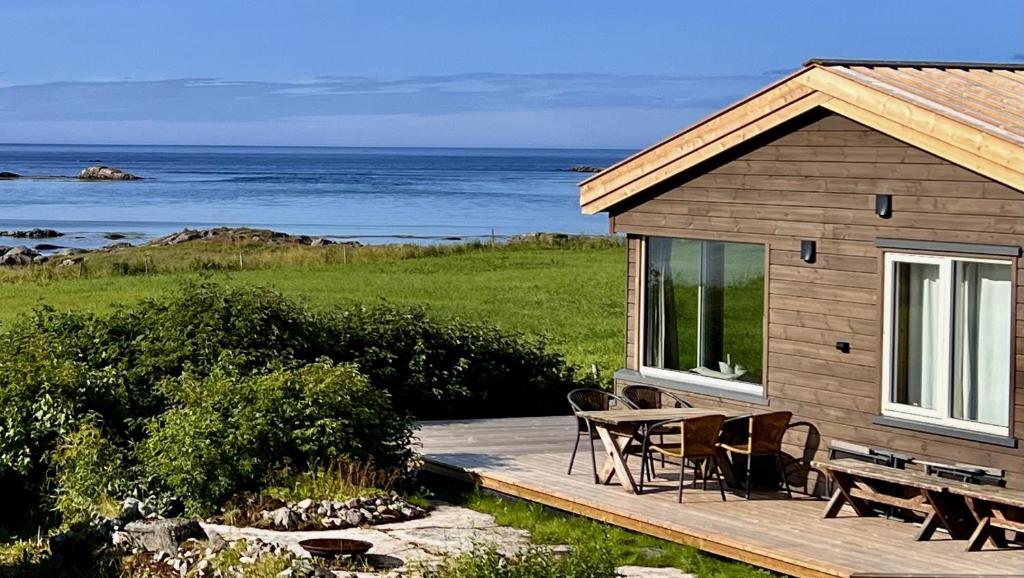 a house with a deck with a table and chairs at Sandsbu Cabin - Gimsøy Lofoten in Gimsøy