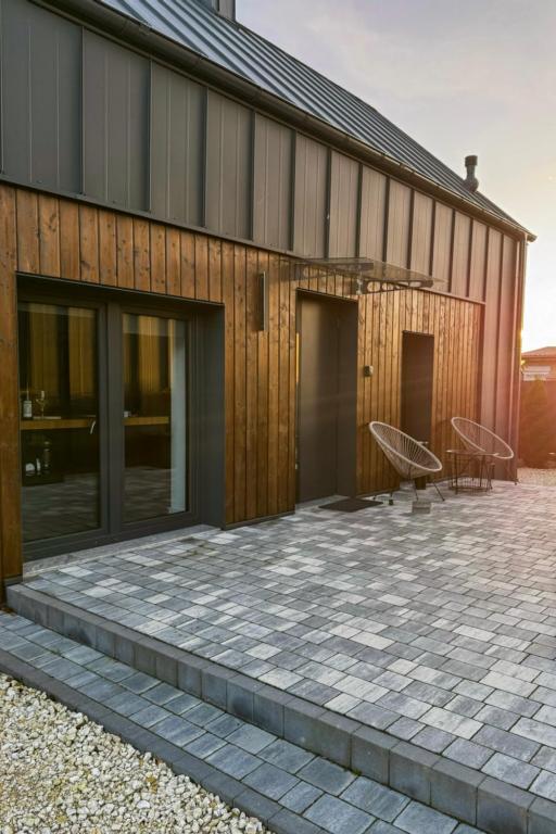 a house with a stone patio next to a building at Siedlisko 3 Stodoły Bałtów - SPA w naturze in Bałtów