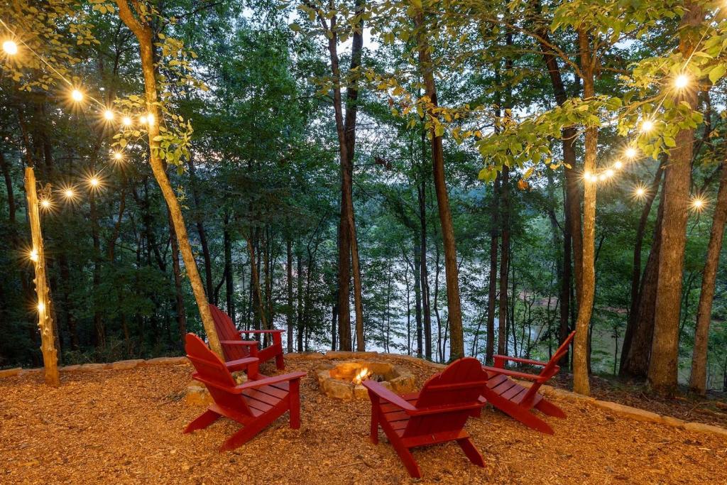 four red chairs around a fire pit in the woods at Private Cozy Lake Escape in Lula
