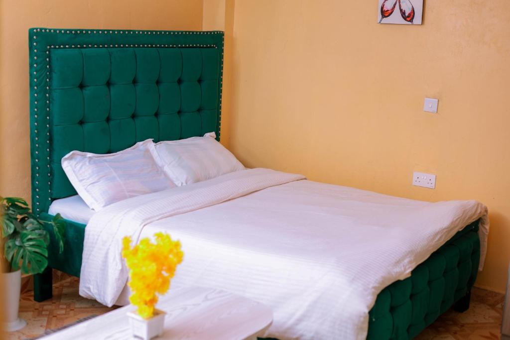 a bed with a green headboard in a room at Monett Bay in Wajir