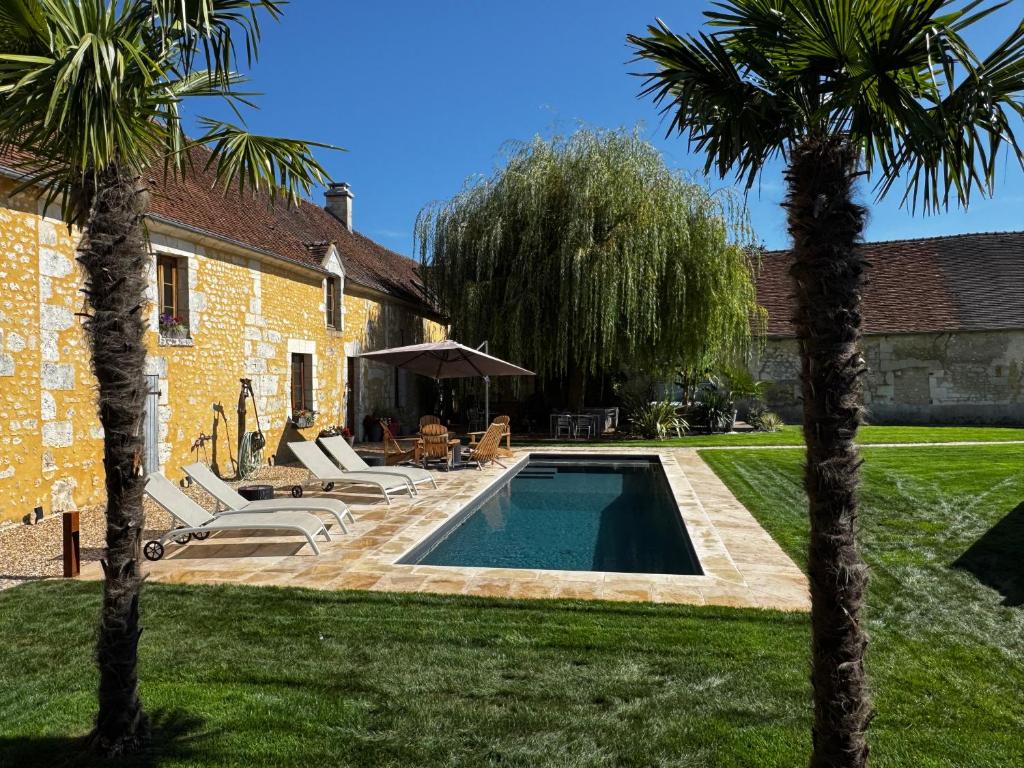 a backyard with a swimming pool and two palm trees at Le Relai Valdieu in Courgeon