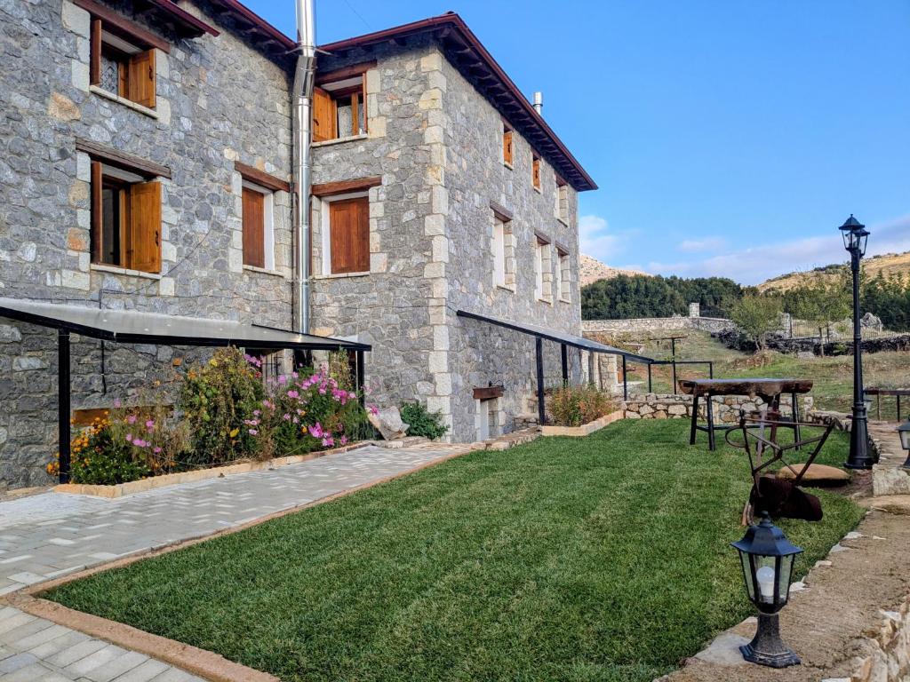 a stone building with a grass yard in front of it at Diminio 3 Apartment at Livadi Arachova in Arachova