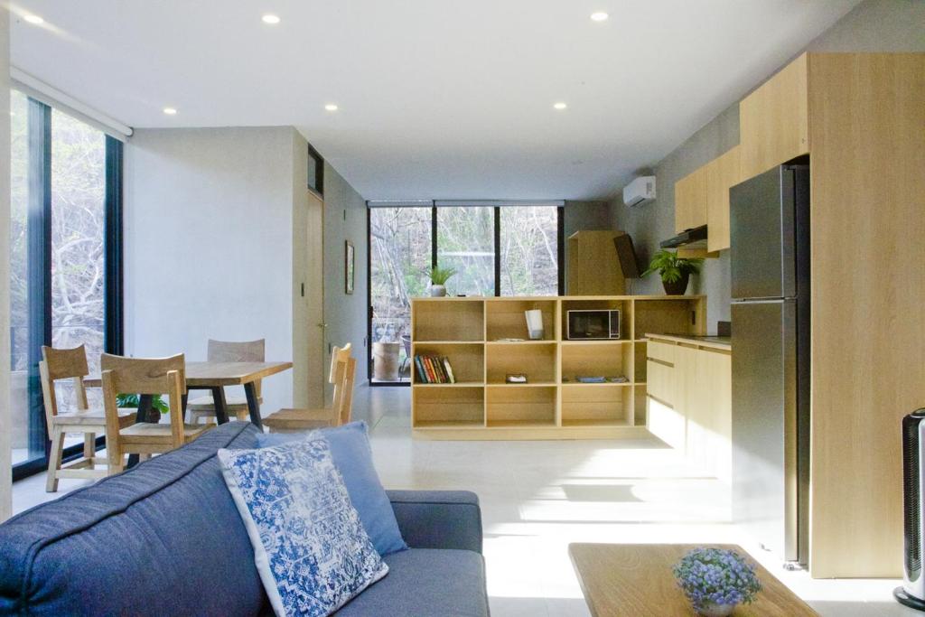 ein Wohnzimmer mit einer blauen Couch und einer Küche in der Unterkunft TerraCondos Loft 203 & 204 in Bahías de Huatulco