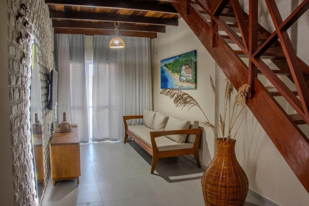 ein Wohnzimmer mit einem Sofa und einer Vase in der Unterkunft Casa Hygge - Conforto, estilo e momentos únicos! in Tamandaré