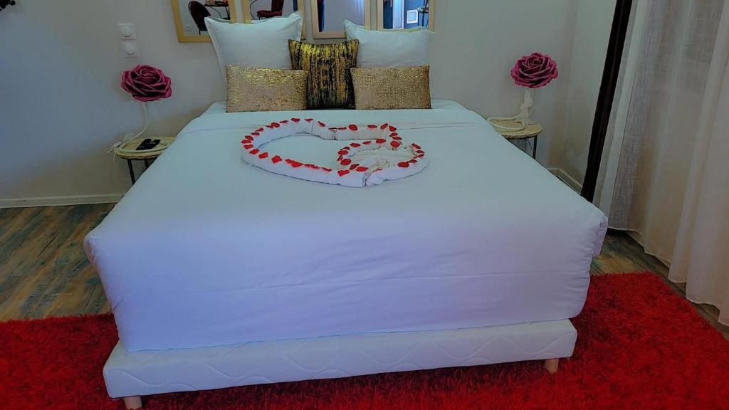 a white bed with a heart made up on it at La Cachette Fleurie in Hésingue