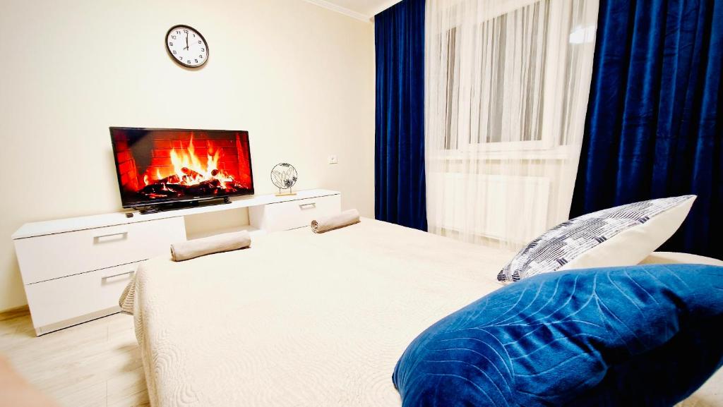 a bedroom with a bed with a tv and a couch at M&M Apartment V SELF CHECK-IN in Panevėžys