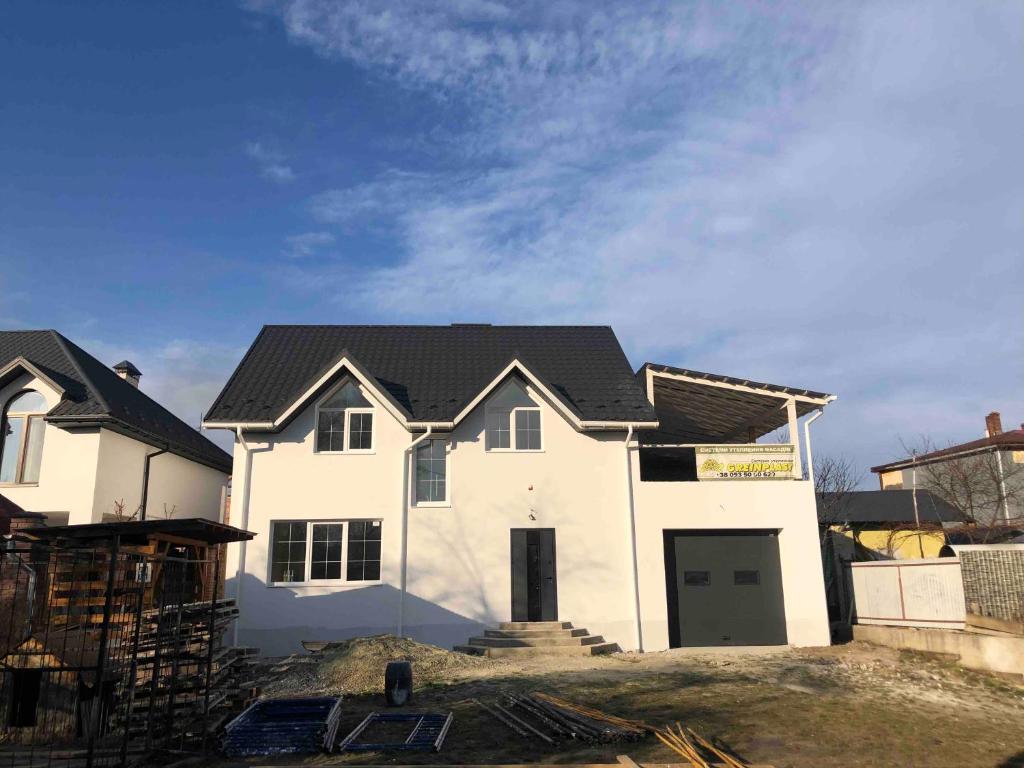 une maison en construction avec un toit noir dans l'établissement Будинок для відпочинку, à Borysxaw