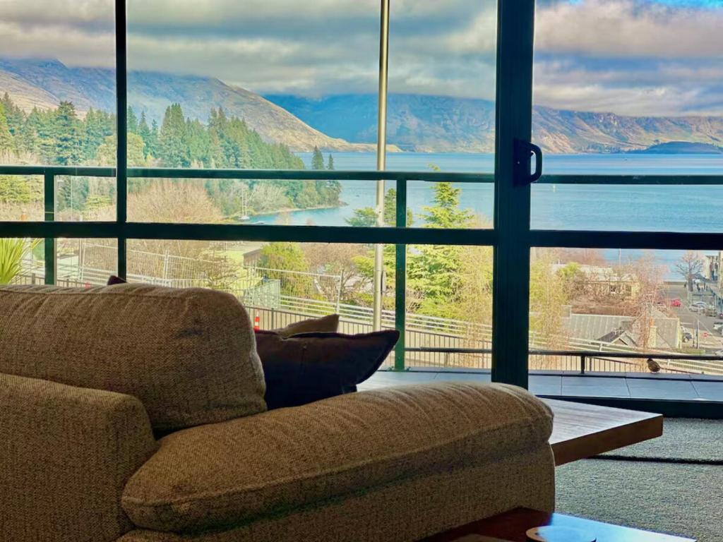 a living room with a couch and a large window at Stunning Lake Views in Queenstown