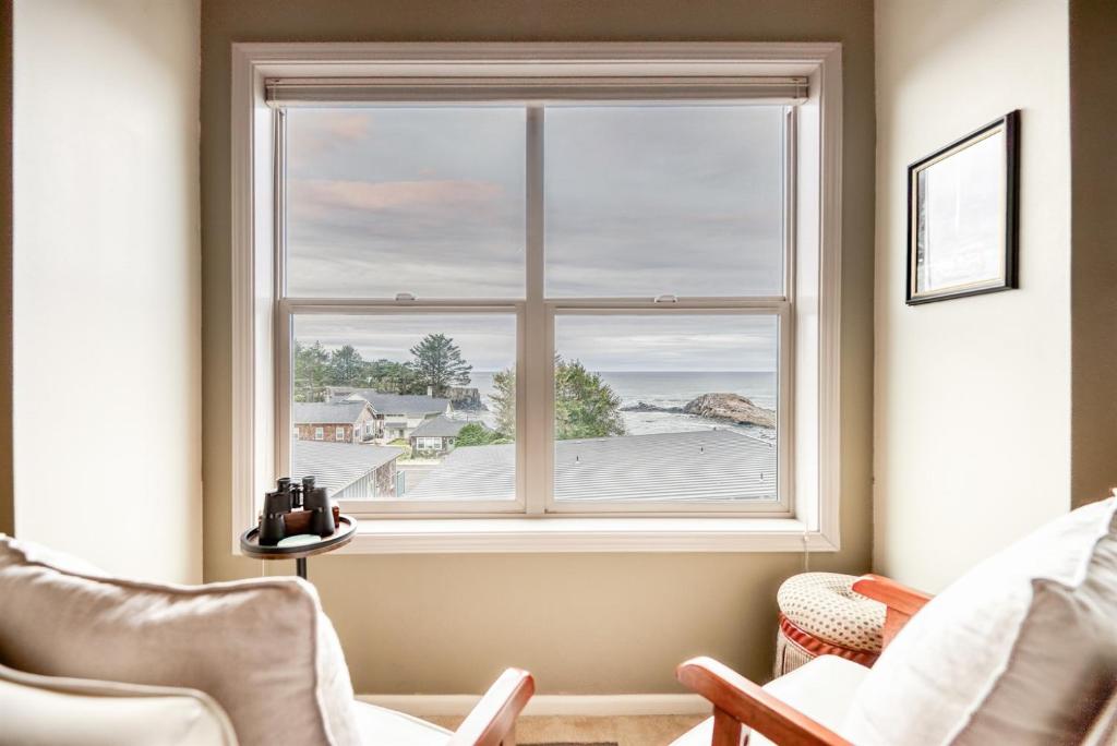 a window in a room with chairs and a view at Stunning Oceanview Townhouse Walk to Seawall, Shops & Depoe Bay Dining in Depoe Bay