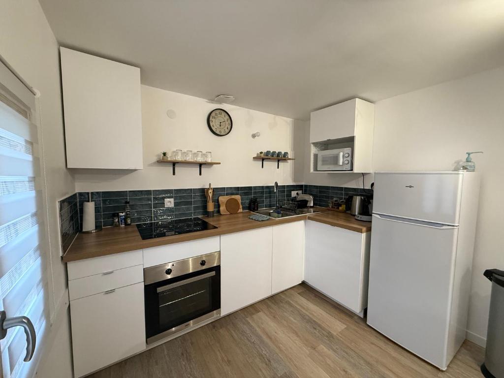a kitchen with white cabinets and a refrigerator at La Rêverie in Le Thor