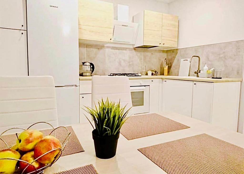 een keuken met witte kasten en een fruitschaal op een tafel bij M&M Apartment I SELF CHECK-IN near Panevezys in Velžys