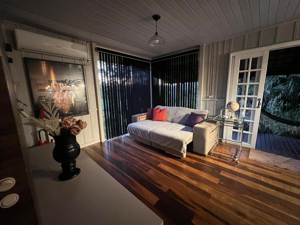 a living room with a white couch and wood floors at Pool amid the green in Gaspar