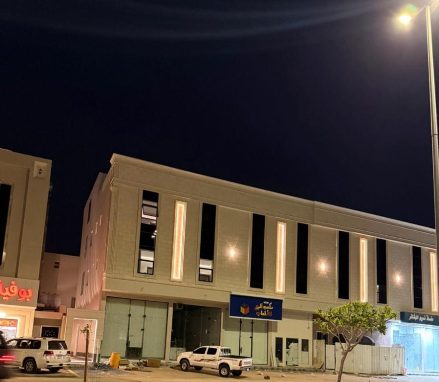 Un edificio con coches aparcados delante por la noche. en شقة مطلة على البرج - غرفه وصالة, en Al Kharj