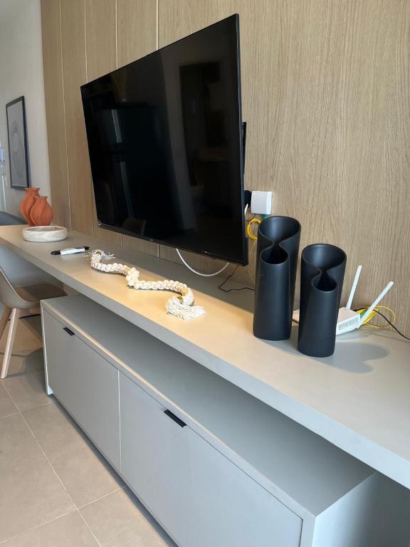 a table with a tv and two black vases on it at Estúdio completo e charmoso in Marília