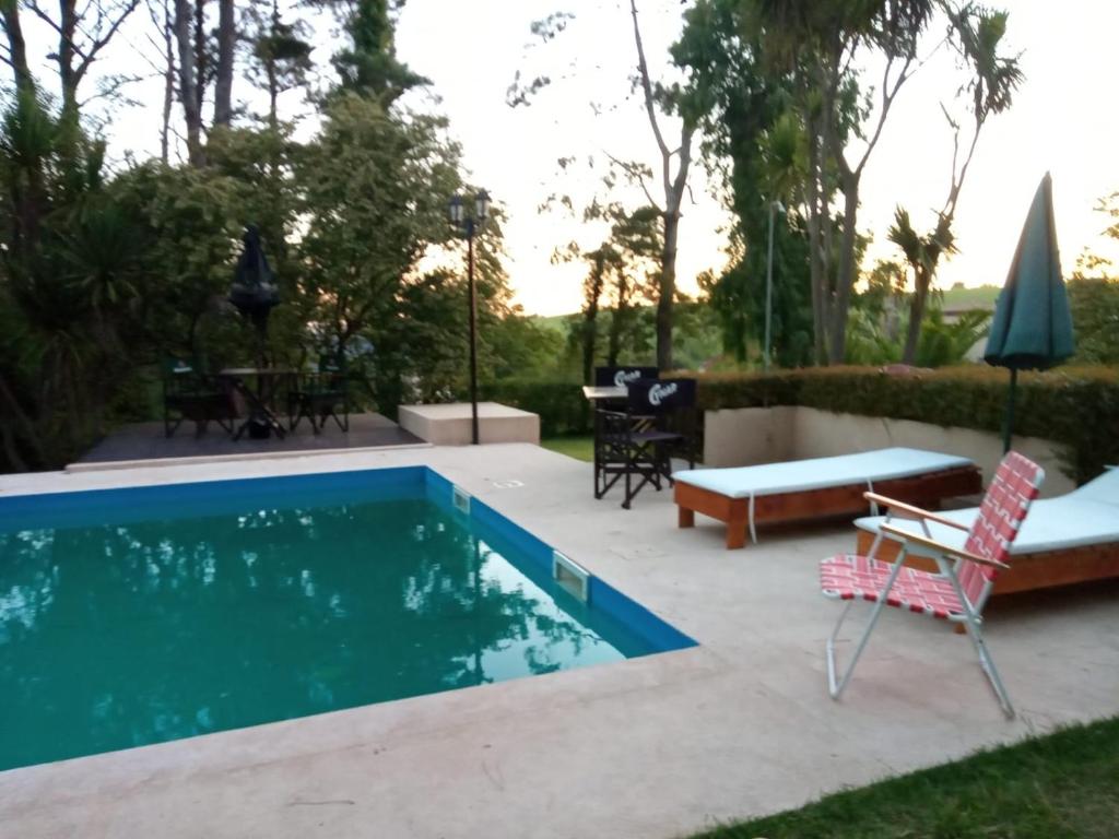 eine Terrasse mit Pool, Stühlen und einem Tisch in der Unterkunft casa Sierras in Sierra de los Padres