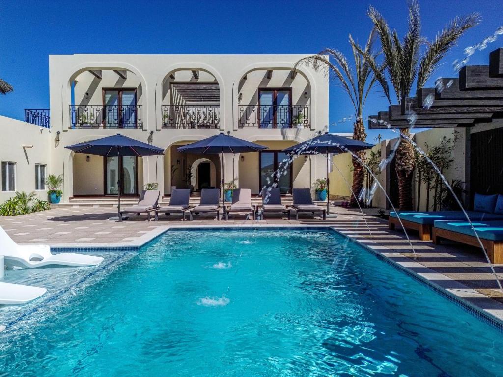 a pool with chairs and umbrellas in front of a house at Paz del Mar 9 in Cedro