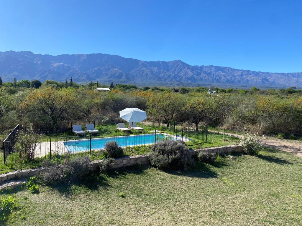 une piscine avec deux chaises et un parasol dans l'établissement Casa de Las Brujas Traslasierra, à Los Molles