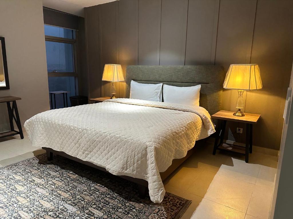 a bedroom with a large white bed with two lamps at 1 Constitution Avenue By Goldfinch in Islamabad
