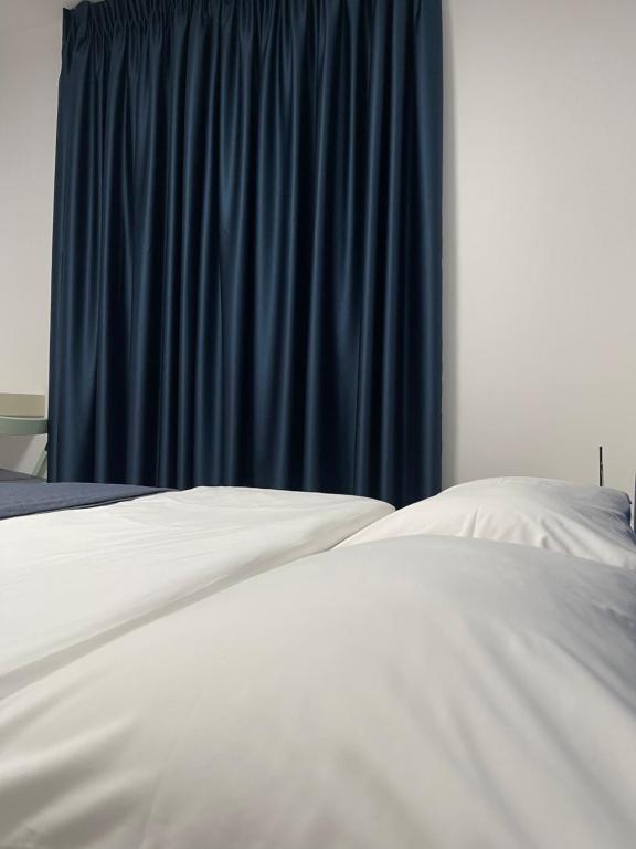 a bed with white sheets and a blue curtain at Vibe Comfort Tirana in Tirana