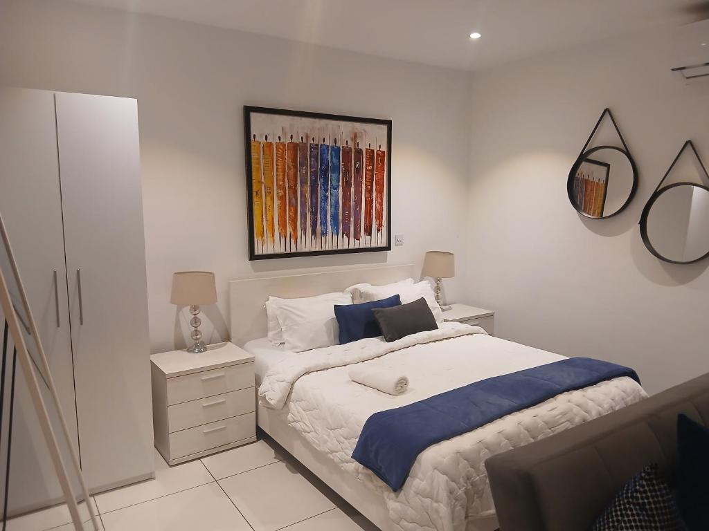 ein Schlafzimmer mit einem Bett und einem Gemälde an der Wand in der Unterkunft Embassy Gardens- Frank Homes in Accra