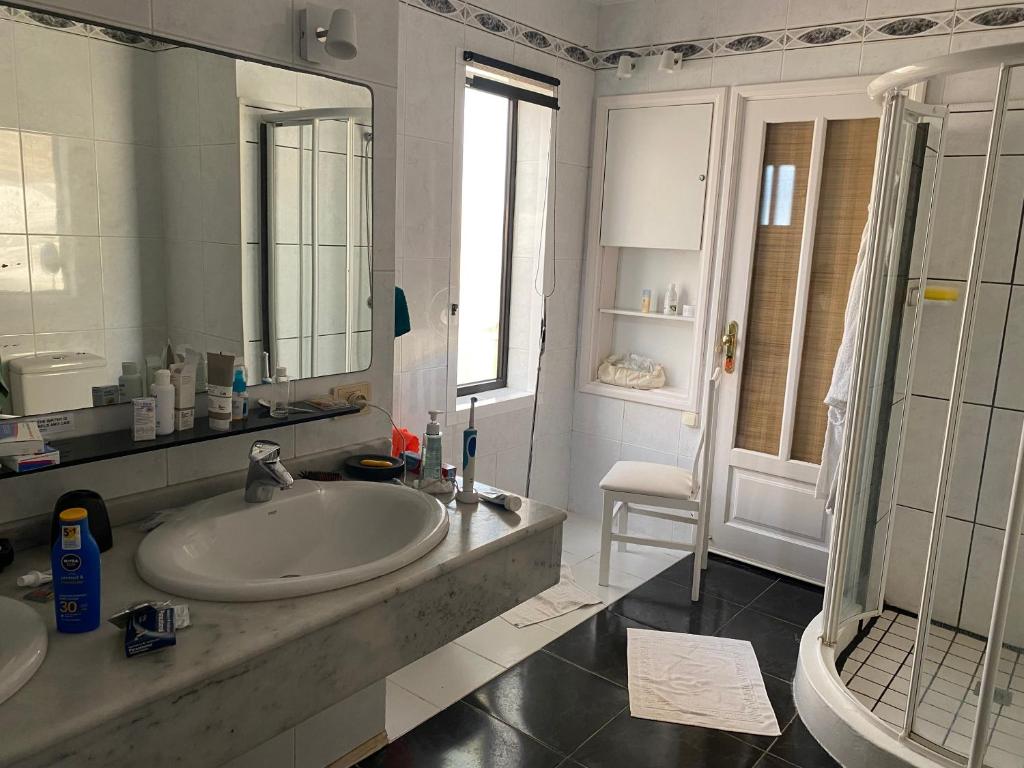 a white bathroom with a sink and a shower at Villa Los Ojos in Charco del Palo