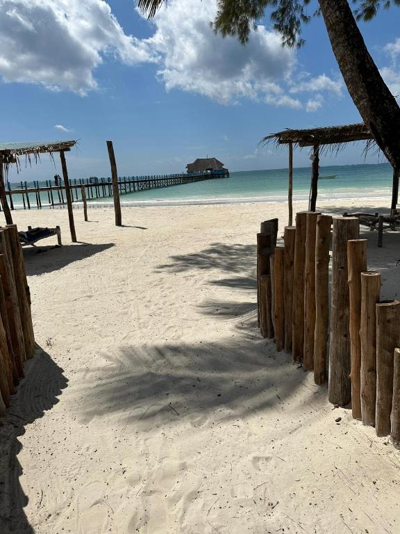 a beach with a wooden fence and the ocean at Maisha Marefu Apartments in Kiwengwa