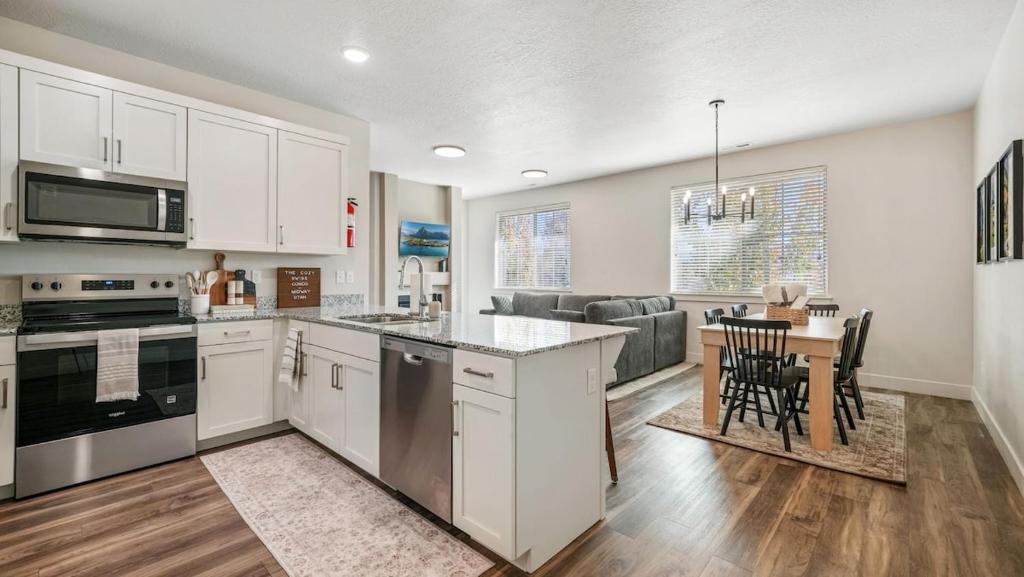 una cucina e un soggiorno con armadi bianchi e tavolo di Cozy Swiss Condo -King Bed, Sleeps 6, Free Blanket a Midway