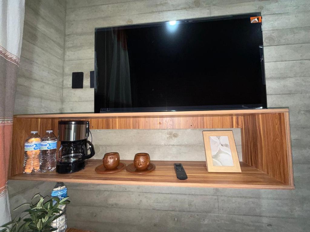 a television on a wall with a shelf with a remote control at Casa Don Tacho in Cedro