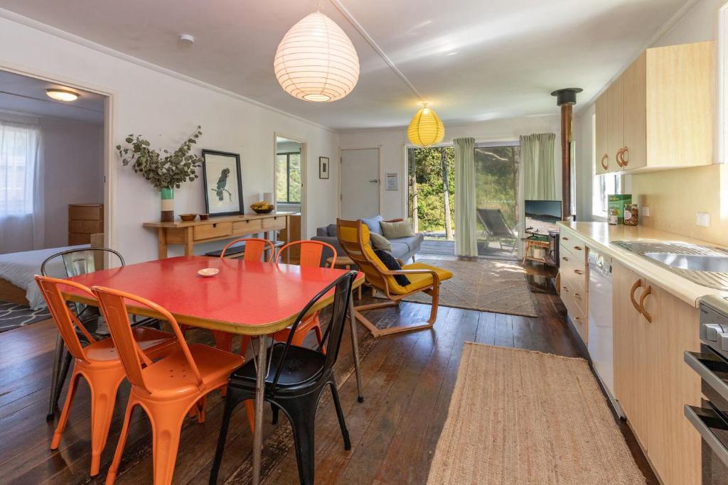 a kitchen and dining room with a red table and chairs at Pippis a Classic Beach House in Seal Rocks