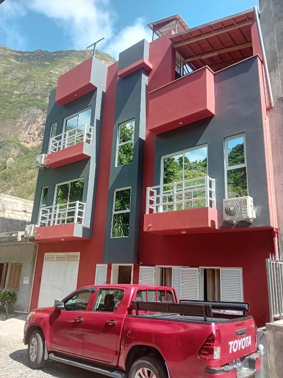 a red truck parked in front of a red house at Residencial Chez Flávia in Pombas